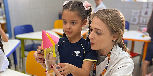 Menina com a professora, desenvolvendo atividade em sala de aula