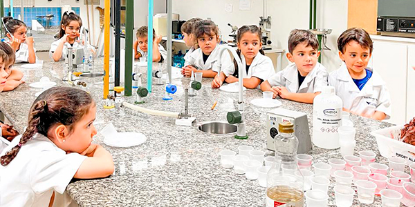 Criança sorrindo sendo recebida na escola 